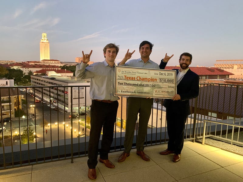 Three men hold an oversized check and use the Hook ’em Horns hand symbol